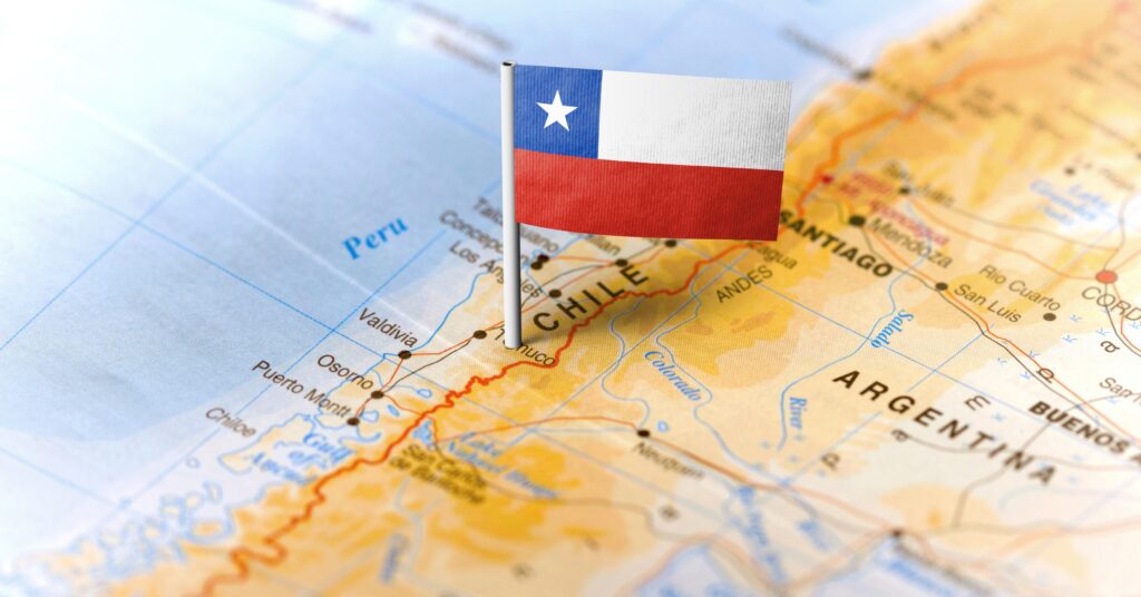 Close-up of a physical map with a miniature Chilean flag pinpointing the country’s location in South America — ideal visual for planning a move to Chile from the US.